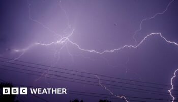 Night sky turning a purple hue as fork lighting spreads across the sky.