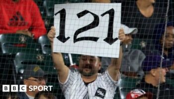 A fan holds up a '121' sign to mark the Chicago White Sox's record defeat