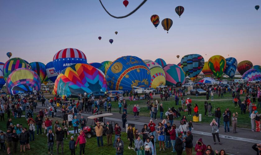 People watch as Meow Wolf's Skyworm hot air balloon takes flight during the Albuquerque International Balloon Fiesta at Balloon Fiesta Park in Albuquerque, N.M., on Tuesday, Oct. 8, 2024. (Chancey Bush/The Albuquerque Journal via AP)