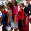 Palestinian children queue to receive food cooked by a charity kitchen  in Khan Younis