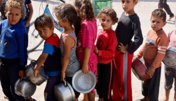 Palestinian children queue to receive food cooked by a charity kitchen  in Khan Younis