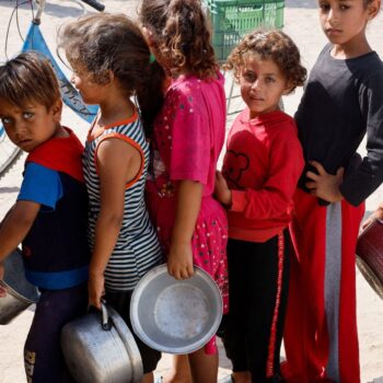 Palestinian children queue to receive food cooked by a charity kitchen  in Khan Younis