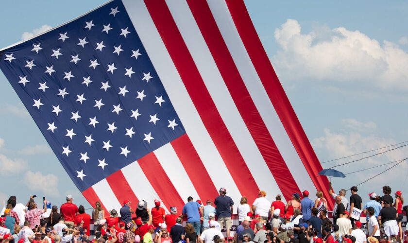 Le drapeau américain flotte au dessus de sympathisants venus assister au meeting où Donald Trump a été la cible de tirs à Butler (nord-est des Etats-Unis), le 13 juillet 2024