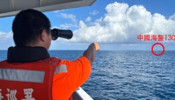 Photo diffusée par les gardes-côtes taïwanais, le 14 octobre 2024, d'un garde-côte taïwanais, sur un navire pétrolier au large de l'îlot Pengjia, observant aux jumelles un navire des gardes-côtes chinois naviguant en dehors des eaux territoriales de Taïwan