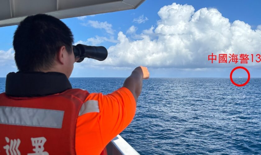 Photo diffusée par les gardes-côtes taïwanais, le 14 octobre 2024, d'un garde-côte taïwanais, sur un navire pétrolier au large de l'îlot Pengjia, observant aux jumelles un navire des gardes-côtes chinois naviguant en dehors des eaux territoriales de Taïwan