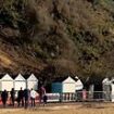 Terrifying moment man comes within inches of being wiped out by flying beach hut as landslide hits popular beach