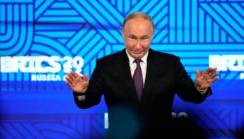 Russlands Präsident Wladimir Putin breitet vor dem Logo des Brics-Gipfels 2024 die Hände aus