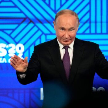 Russlands Präsident Wladimir Putin breitet vor dem Logo des Brics-Gipfels 2024 die Hände aus