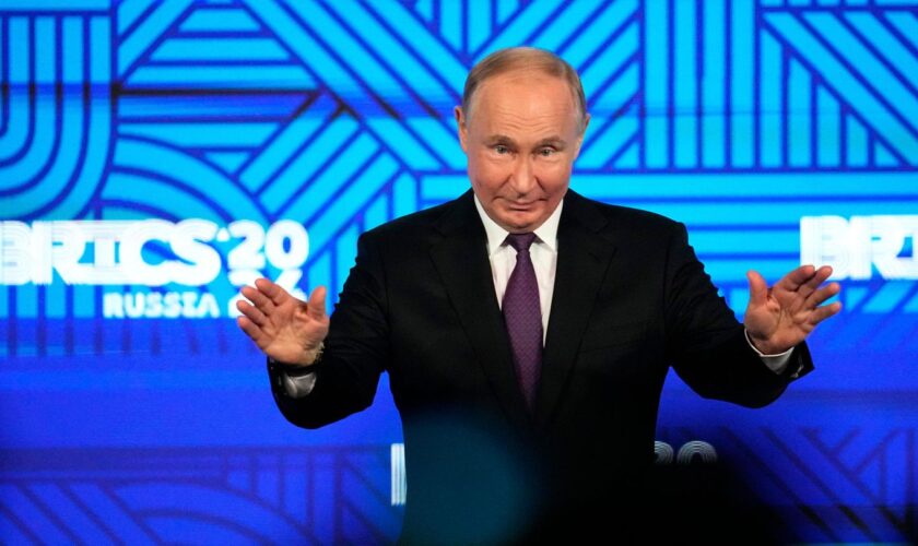 Russlands Präsident Wladimir Putin breitet vor dem Logo des Brics-Gipfels 2024 die Hände aus