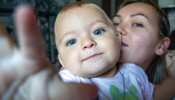 Kinder kriegen: Eine Mutter hält ihr Baby auf dem Arm. Beide schauen in die Kamera