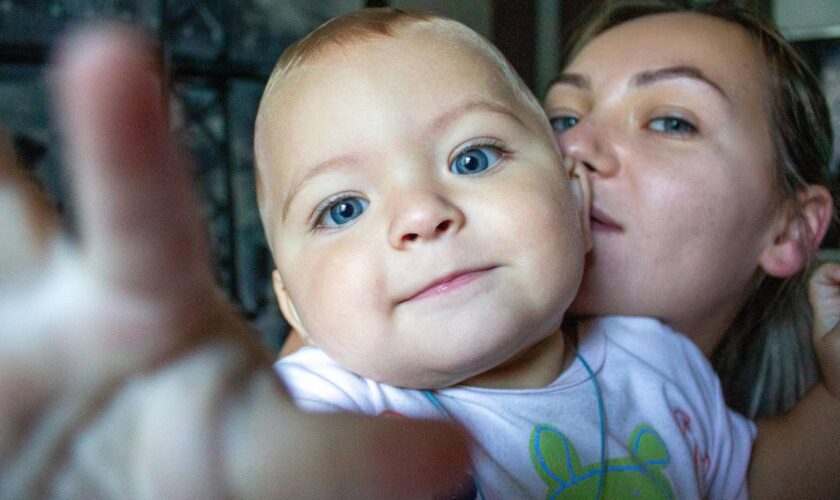 Kinder kriegen: Eine Mutter hält ihr Baby auf dem Arm. Beide schauen in die Kamera