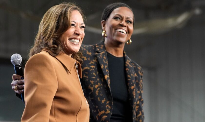 Former first lady Michelle Obama, right, and Democratic presidential nominee Vice President Kamala Harris address the crowd in the overflow space of a campaign rally at the Wings Event Center in Kalamazoo, Mich. (AP Photo/Jacquelyn Martin)