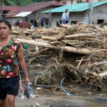 A resident passes by toppled trees after a landslide was triggered by Tropical Storm Trami. Pic: AP Photo/Aaron Favila