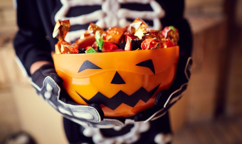 Boy in skeleton costume holding bowl full of candies