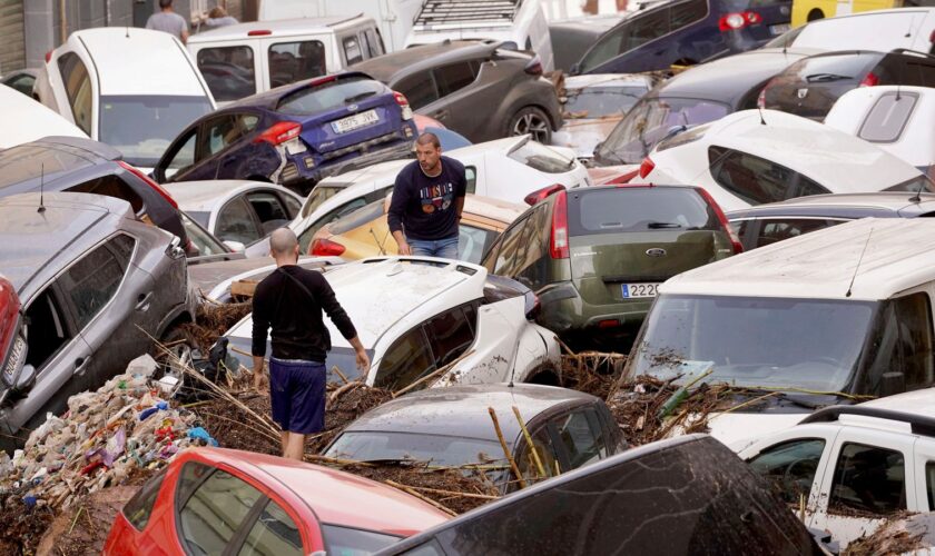 Residents look at cars piled up after being swept away by floods in Valencia, Spain, Wednesday, Oct. 30, 2024. (AP Photo/Alberto Saiz)