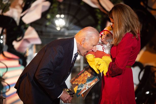 Joe Biden bites baby's leg and sticks tot's foot in his mouth as kids come dressed for Halloween