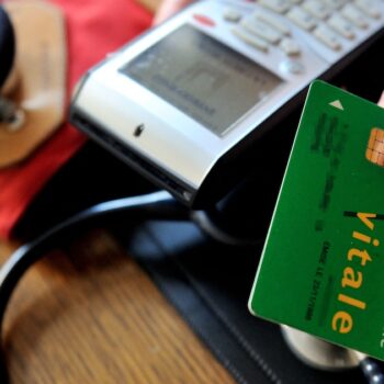 A doctor gives back a French health insurance electronic card (carte vitale) after using it in a connected reader on September 23, 2013 in Godewaersvelde, northern France, during medical exams.  AFP PHOTO / PHILIPPE HUGUEN (Photo by PHILIPPE HUGUEN / AFP)