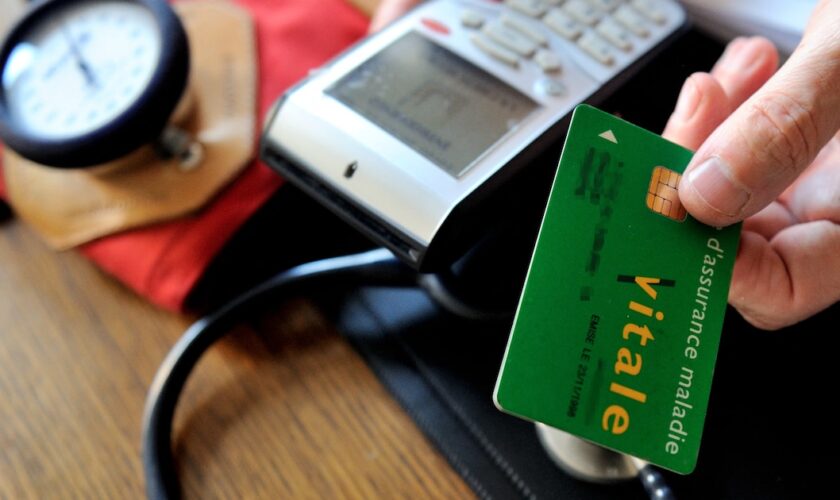 A doctor gives back a French health insurance electronic card (carte vitale) after using it in a connected reader on September 23, 2013 in Godewaersvelde, northern France, during medical exams.  AFP PHOTO / PHILIPPE HUGUEN (Photo by PHILIPPE HUGUEN / AFP)