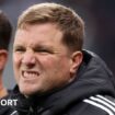 Eddie Howe and one other person talk as they kneel on a pitch