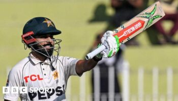 Pakistan batter Saud Shakeel raises his bat to celebrate hitting a century