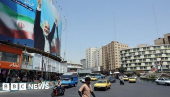 Cars and people on a street in Tehran with a large billboard showing an image of former Hamas leader Ismail Haniyeh (file photo)