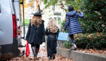 Mann öffnet Kindern an Halloween Tür mit Gewehr in der Hand