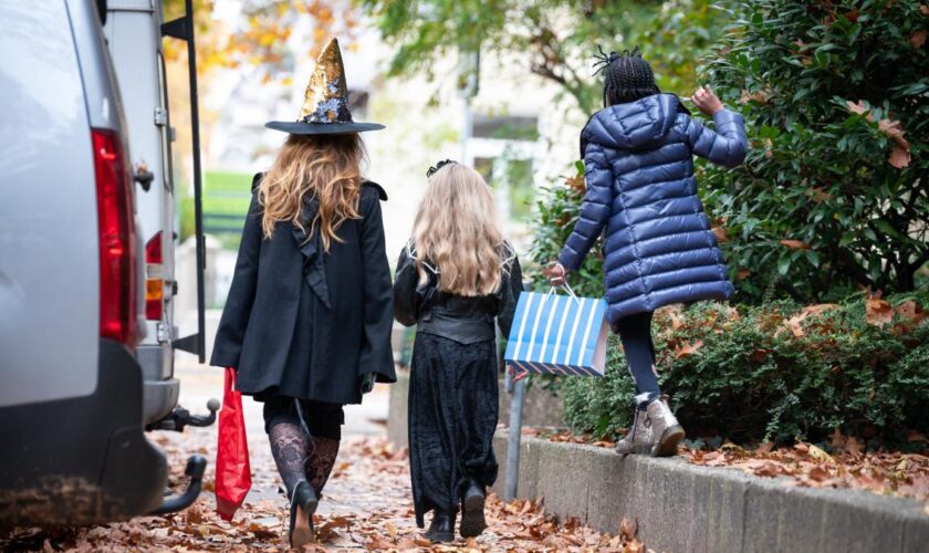 Mann öffnet Kindern an Halloween Tür mit Gewehr in der Hand