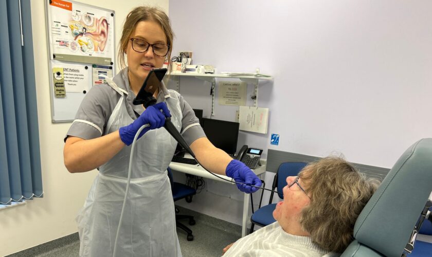 Nina Glazzard, an advanced clinical practitioner for ears, nose and throat, using an endoscope-I adapter on Janet Hennessy, 76, from Bradeley, Stoke-on-Trent, as part of a trial at North Midlands University Hospitals NHS Trust. The adapter includes a 32mm lens that attaches to an iPhone, turning it into a portable endoscope to help the NHS rule out throat cancer in patients faster. Issue date: Saturday November 2, 2024.