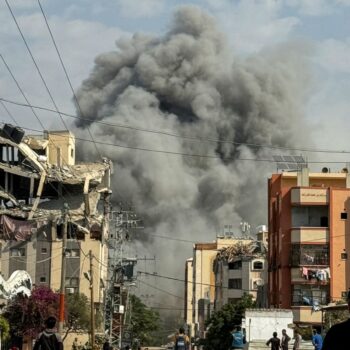 Palestinians watch as smoke rises following Israeli strikes in Nuseirat in the central Gaza Strip. Pic: Reuters