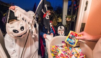 Kinder bekommen zu Halloween Süßigkeiten an einer Haustür