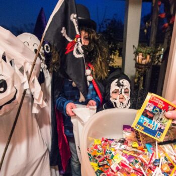 Kinder bekommen zu Halloween Süßigkeiten an einer Haustür