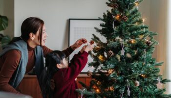 Mutter und Kind schmücken einen Tannenbaum.