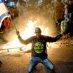 A protester holds an Israeli flag as Israelis light a bonfire during a protest after Prime Minister Benjamin Netanyahu has dismissed his defense minister Yoav Gallant in a surprise announcement in Tel Aviv, Israel, Tuesday, Nov. 5, 2024. (AP Photo/Francisco Seco)