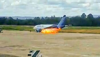 Terrifying moment passengers leap from plane emergency exit as flames billow from engine