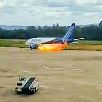 Terrifying moment passengers leap from plane emergency exit as flames billow from engine