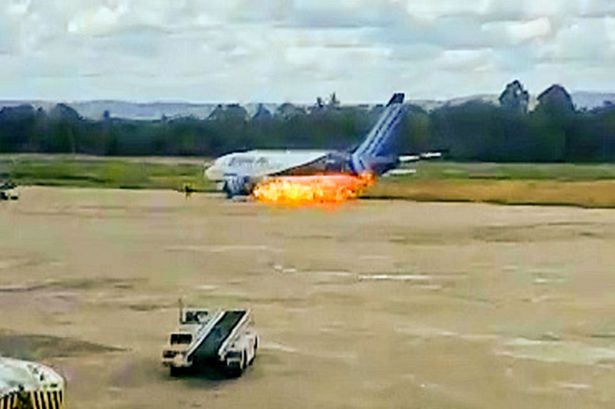 Terrifying moment passengers leap from plane emergency exit as flames billow from engine