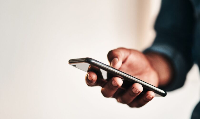 Cropped shot of an unrecognizable businessman standing alone in his home office and texting on his cellphone