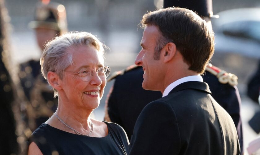 France's President Emmanuel Macron (R) and France's Prime Minister Elisabeth Borne chat as they wait for the arrival of the Indian Prime Minister ahead of a dinner at The Louvre Museum in Paris, on July 14, 2023. (Photo by Ludovic MARIN / AFP)