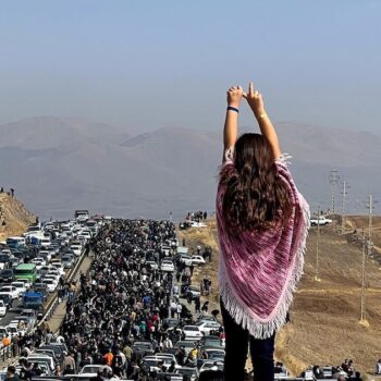 Image UGC publiée sur Twitter, le 26 octobre 2022, d'une femme non voilée debout sur le toit d'une voiture, des milliers de personnes se dirigeant vers un cimetière à Saghez, dans l'ouest de l'Iran, pour marquer le 40e jour du décès de Mahsa Amini