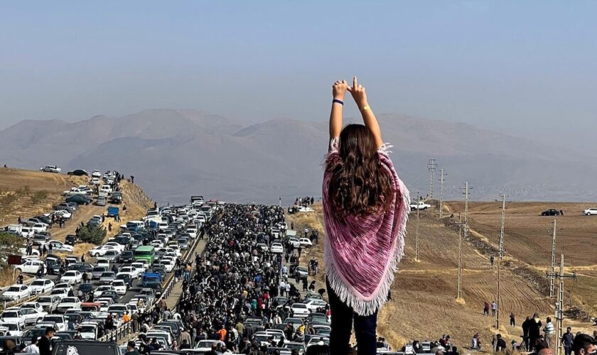 Image UGC publiée sur Twitter, le 26 octobre 2022, d'une femme non voilée debout sur le toit d'une voiture, des milliers de personnes se dirigeant vers un cimetière à Saghez, dans l'ouest de l'Iran, pour marquer le 40e jour du décès de Mahsa Amini