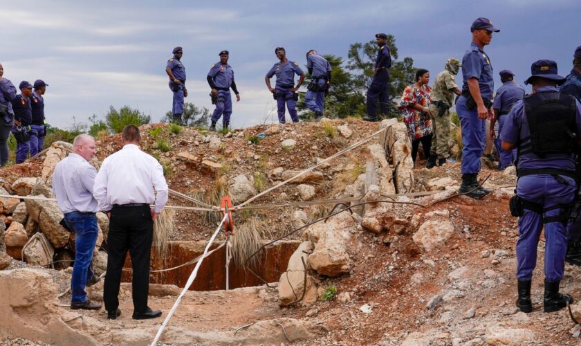 Police officers and private security personnel at the entrance to the mine in Stilfontein, South Africa. Pic: AP/Denis Farrell