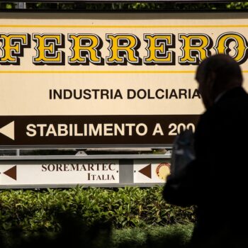 Cette photo prix le 29 mai 2019 à Alba montre un homme marchant près du logo du fabricant italien de chocolat de marque Ferrero.