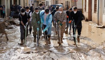 Des personnes et des soldats participent à une opération de nettoyage dans une rue inondée à Catarroja, dans la région de Valence, dans l'est de l'Espagne, à la suite d'inondations meurtrières, le 6 novembre 2024