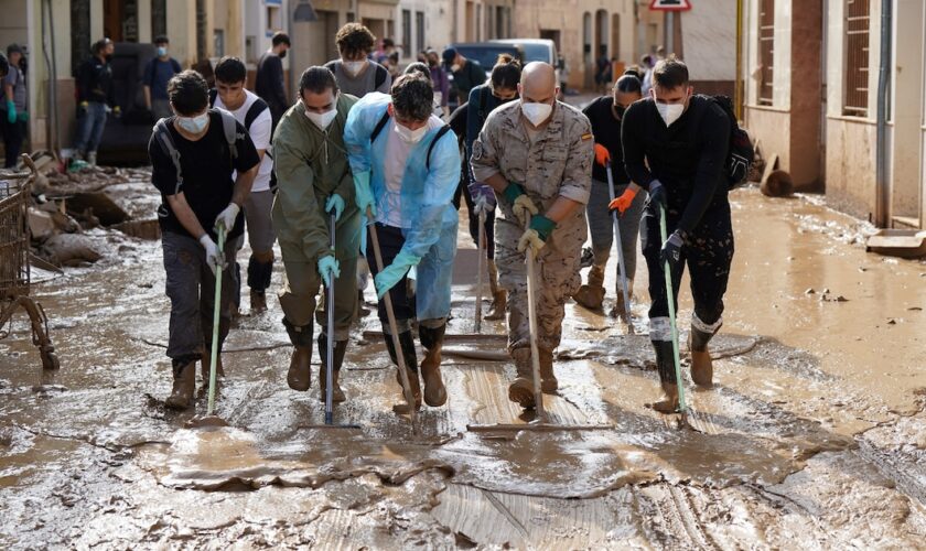 Des personnes et des soldats participent à une opération de nettoyage dans une rue inondée à Catarroja, dans la région de Valence, dans l'est de l'Espagne, à la suite d'inondations meurtrières, le 6 novembre 2024