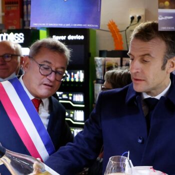 Le président français Emmanuel Macron (à droite) et le maire de Vierzon, Nicolas Sansu (à gauche), boivent un verre de vin dans un café de la ville de Vierzon, le 7 décembre 2021. (Photo de Ludovic MARIN / AFP)