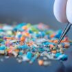 Macro shot of a person with medical gloves and tweezers inspecting a pile of micro plastics. Concept of water pollution and global warming. Macro shot of micro plastics. Cool blue filter applied.