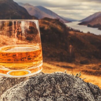 Glass of single malt Scotch Whisky on an old rock above Glenfinnan in the West Highlands of Scotland.