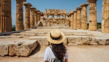 Eine Frau steht vor den antiken Ruinen in Athen.