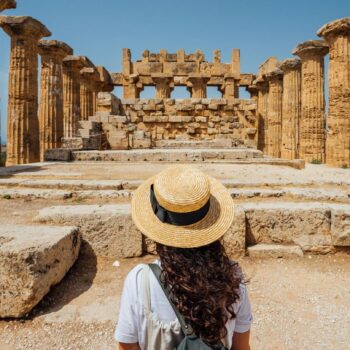 Eine Frau steht vor den antiken Ruinen in Athen.