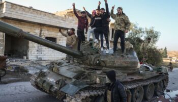 Opposition supporters stand on a captured Syrian army tank near Aleppo. Pic: AP Photo/Omar Albam